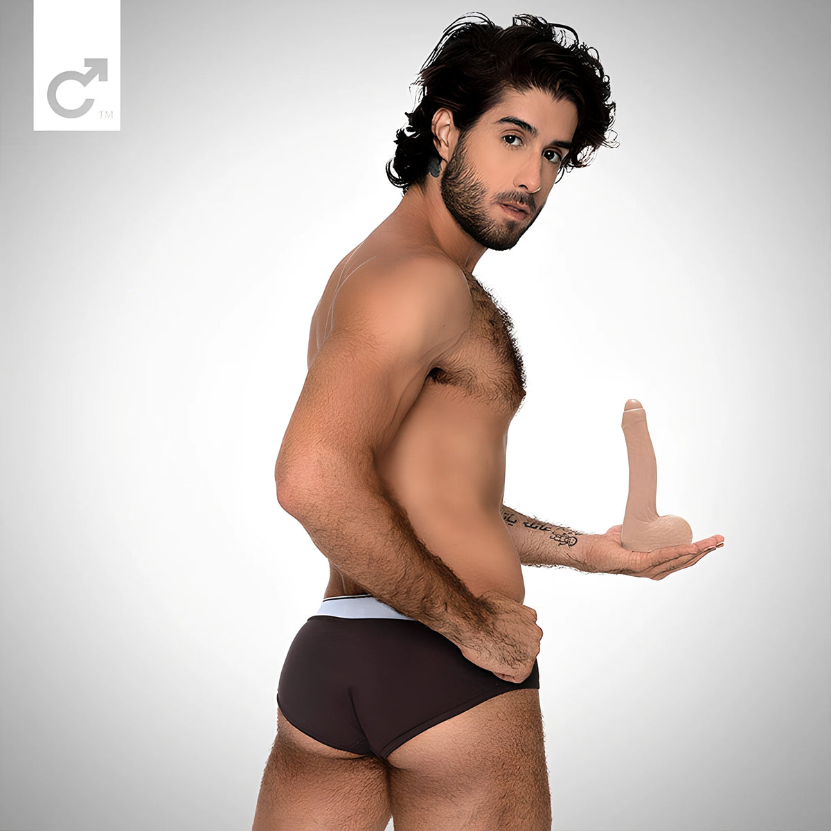 Мъж по тъмни слипове държи в дланта си дилдото Diego Sans на Fleshlight, телесен цвят, за показване на размера