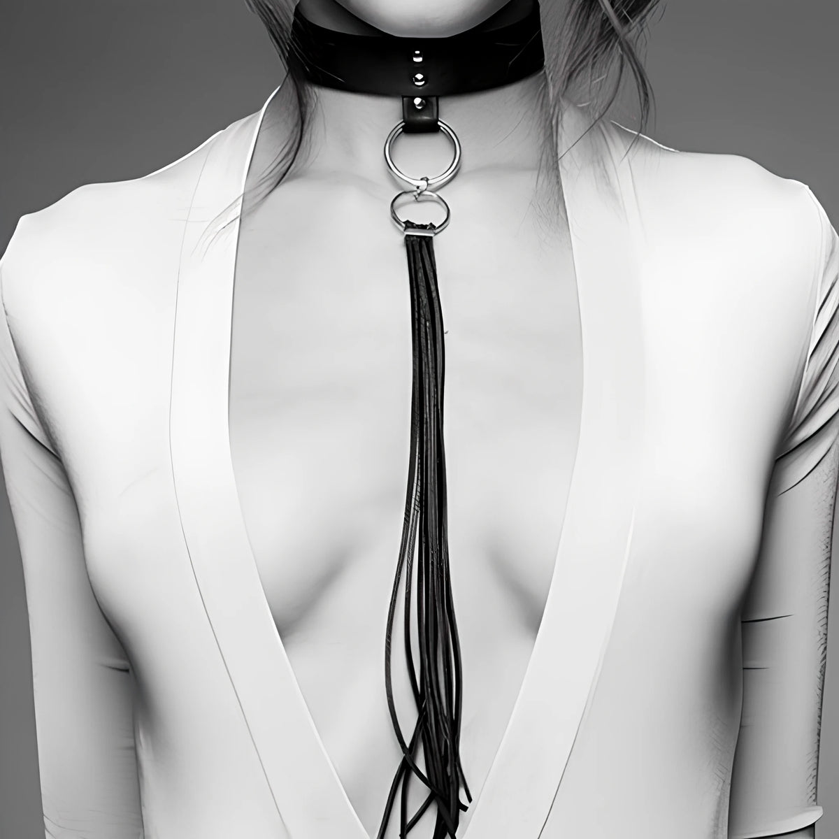 Нашийник с пискюл MAZE на Bijoux Indiscrets: черна кожена лента с метални капси, две халки и дълги ресни върху модел в бяла дреха