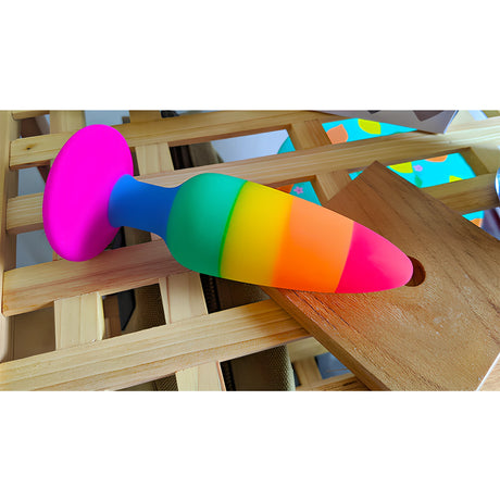 Анален разширител Colours Pride Edition 13 см в дъговидни цветове, поставен върху дървена решетка, със силиконова розова основа