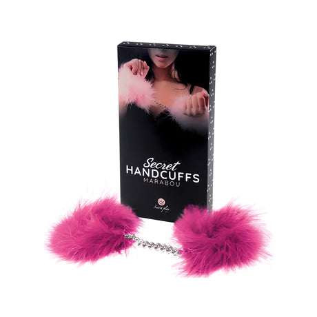 Розови пухкави белезници Marabou със сребриста верижка пред черната кутия на Secret Play с надпис Secret Handcuffs Marabou
