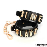 Белезници Slave на LateToBed: две черни кожени гривни със златисти букви SLAVE, закопчани с позлатена верижка с карабинери