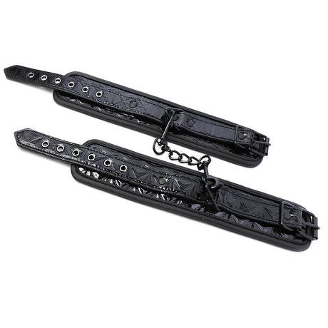 Белезници Black Sapphire на IntoYou – две черни маншети с релефна шарка, перфорирани каишки и къса метална верижка помежду им
