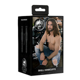 Черна кутия на белезниците Skull Handcuffs от Skulls & Bones с лого с череп и мъж с дълга коса и дънки, носещ белезниците на китките си