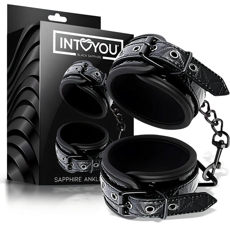 Белезници за крака Black Sapphire на IntoYou: два черни маншета с катарами, свързани с верижка, пред черната им кутия