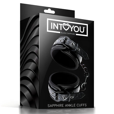 Черна кутия на белезници за крака Black Sapphire на IntoYou с надпис Sapphire Ankle Cuffs и две черни закопчалки с верижка на предната страна