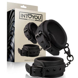 Белезници за крака Black Shadow на IntoYou в черно, с катарами и метална верижка, пред бежавата им кутия с надпис Ankle Cuffs