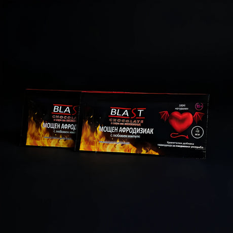 Две черни сашета Blast Chocolate с надпис „Мощен афродизиак с любовен импулс“, пламъци и червено сърце с крилца на опаковката