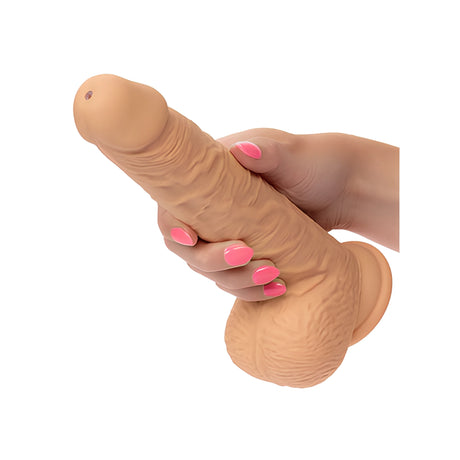 Еякулиращ вибратор Fuck Stick на California Exotic в телесен цвят с вендуза в основата, държан в ръка с розов маникюр за мащаб