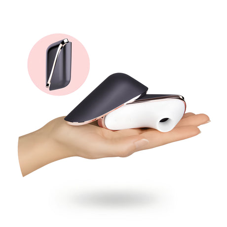 Satisfyer Pro Traveler на дланта за мащаб: бял корпус с отвор и сгъваем тъмносив капак, а в розов кръг – затвореният уред