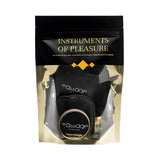 Черно-златист плик на комплект Instruments of Pleasure на Bijoux Indiscrets, през прозореца се виждат масажна свещ и черни аксесоари