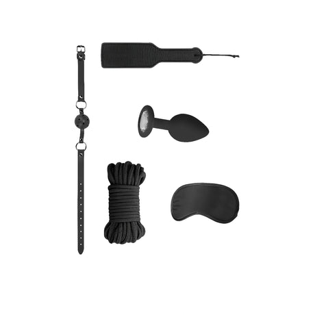 Комплект Introductory Bondage Kit No 5 на Ouch! в черно: каишка с топка, шило, украсена тапа, въже и превръзка за очи, подредени на бял фон