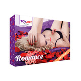 Кутия на комплект Red Romance Gift Set на ToyJoy в лилаво, с жена в черен сутиен сред червени розови листенца