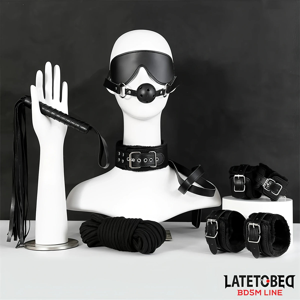 Комплект LateToBed BDSM Line от 7 части в черно: превръзка за очи с топка, нашийник, камшик, въже и маншети, подредени на манекени
