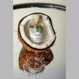 Малко шишенце масажен гел Intt Coconut с топлинен ефект, поставено в половинка кокосов орех върху огледална повърхност с пръски вода