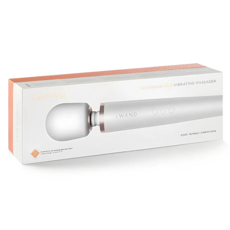 Бяла кутия на масажор Le WAND с розово-златисти акценти и надпис Rechargeable Vibrating Massager, през прозрачен прозорец се вижда продуктът