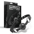 Черен наустник Black Shadow на IntoYou с перфорирана топка и каишка с метални халки, показан пред черната си кутия с лого