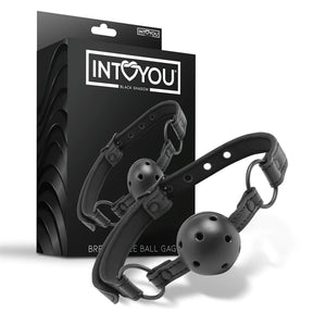 Черен наустник Black Shadow на IntoYou с перфорирана топка и каишка с метални халки, показан пред черната си кутия с лого
