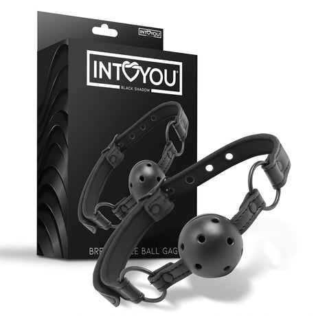 Черен наустник Black Shadow на IntoYou с перфорирана топка и каишка с метални халки, показан пред черната си кутия с лого