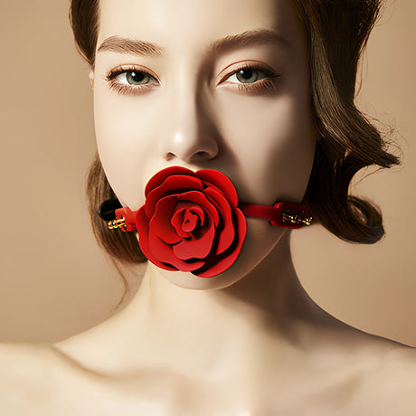 Модел носи наустник Rose Ball Gag на Zalo с червена роза на мястото на топката и червена каишка със златисти катарами
