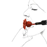 Илюстрация на Наустник Rose Ball Gag на Zalo: червена топка във формата на роза в устата на жена, с черна кожена каишка със златисти нитове
