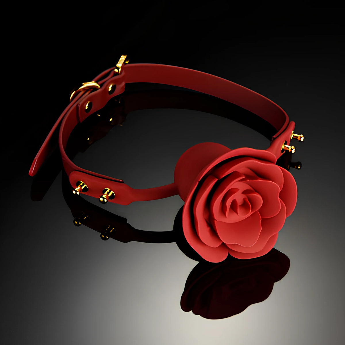 Наустник Rose Ball Gag на Zalo в червено със златисти метални капси и катарама, поставен върху тъмна лъскава повърхност