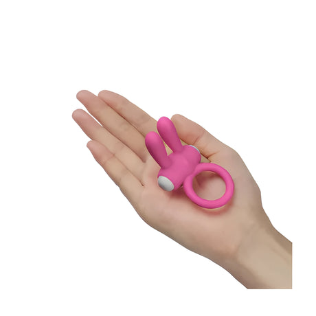 Розов вибриращ пръстен Power Clit на Lovetoy с две заоблени ушички, поставен в дланта на ръка за сравнение на размера