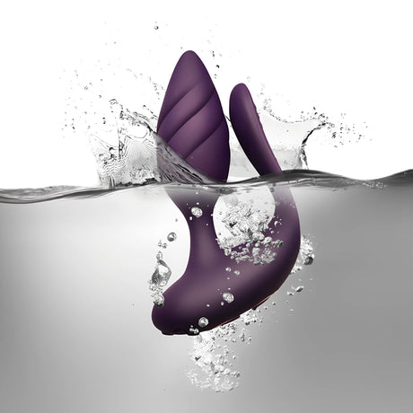 Стимулатор за двойки Cocktail Purple на Rocks-Off в лилав цвят, потопен във вода сред пръски и мехурчета