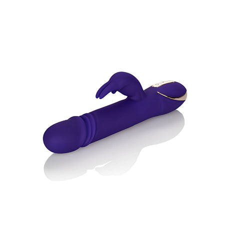 Лилавият вибратор Thrusting Rabbit Signature на California Exotic, поставен настрани, със златист панел с бутони и ребрест връх