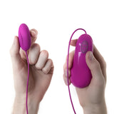 Виброяйце Bnaughty Deluxe Purple в лилаво: яйцето в едната ръка и свързаният с кабел контролер в другата, за сравнение на размера