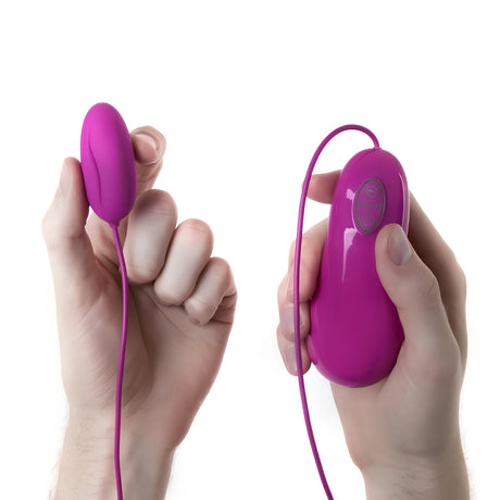 Виброяйце Bnaughty Deluxe Purple в лилаво: яйцето в едната ръка и свързаният с кабел контролер в другата, за сравнение на размера