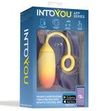 Синя кутия на виброяйце IntoYou App Series с жълто-оранжево яйце на гривна през прозорец и текст за контрол през приложение