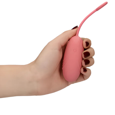 Розово виброяйце Ultra Soft Silicone в дланта на ръка с тъмночервен лак – показва размера, копчето за управление и гъвкавата връзка