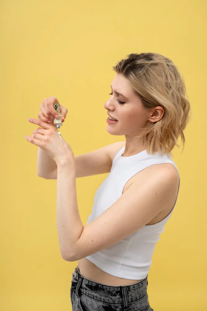 Жена нанася козметичен продукт с пипета върху ръката си, символизираща внимание към състава на продуктите.