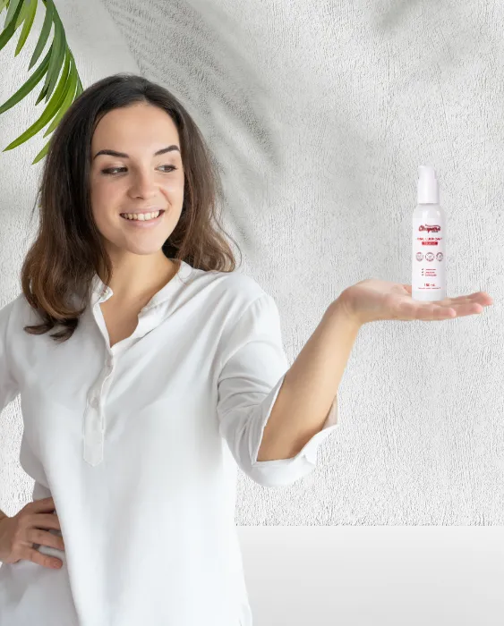 Усмихната жена в бяла риза държи в ръката си анален лубрикант Cleopatra Relaxing – 150 мл, на водна основа, безопасен за латекс.